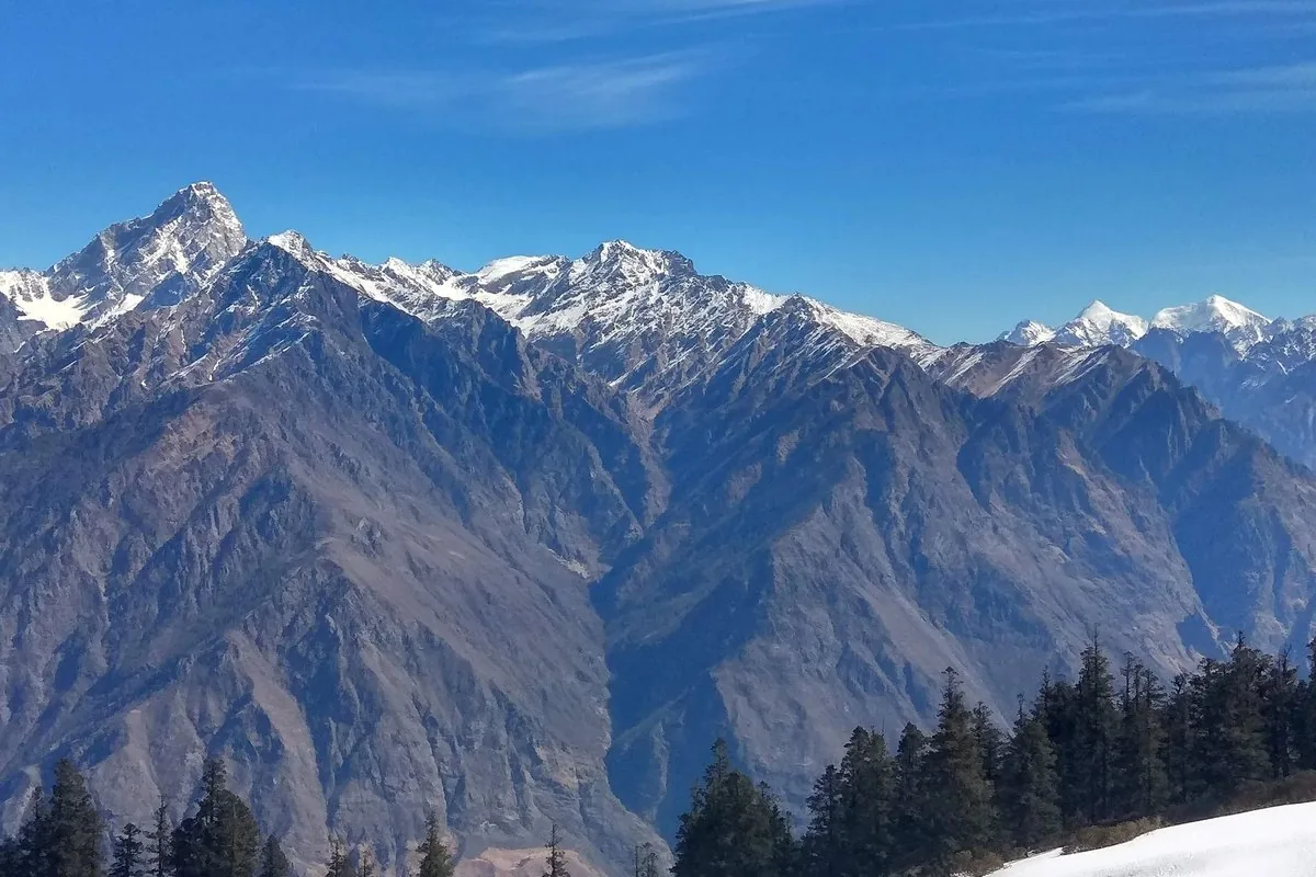 Snow peaks above the forest on the Kuari Pass trail, near the campsites where winter nights fall well below freezing
