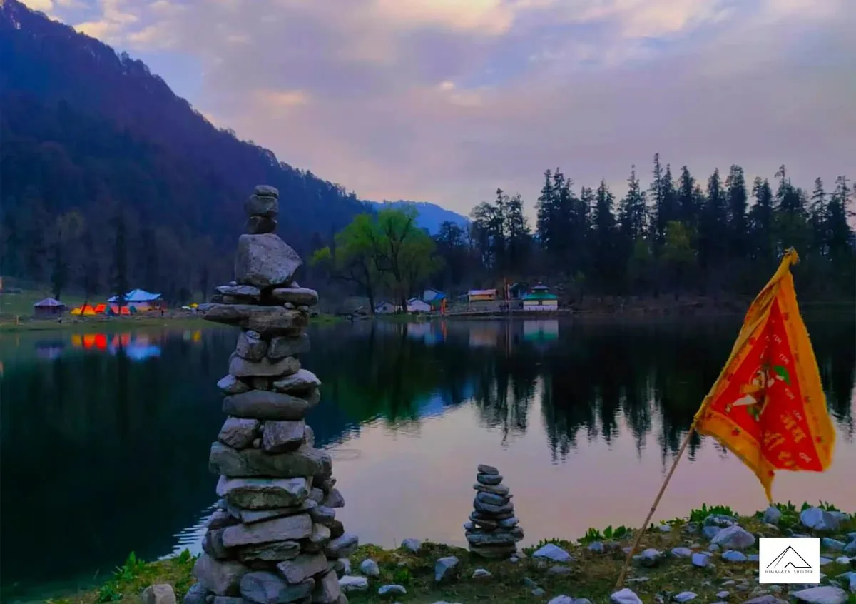 Stone cairns and a saffron religious flag on the shore of Dodital Lake