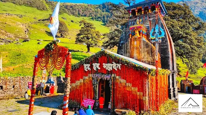 Madhyamaheshwar temple decorated with marigold garlands, with green forested hills behind