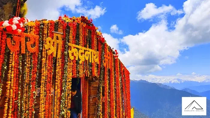 Entrance of Rudranath temple covered in orange and yellow marigold garlands under a blue sky